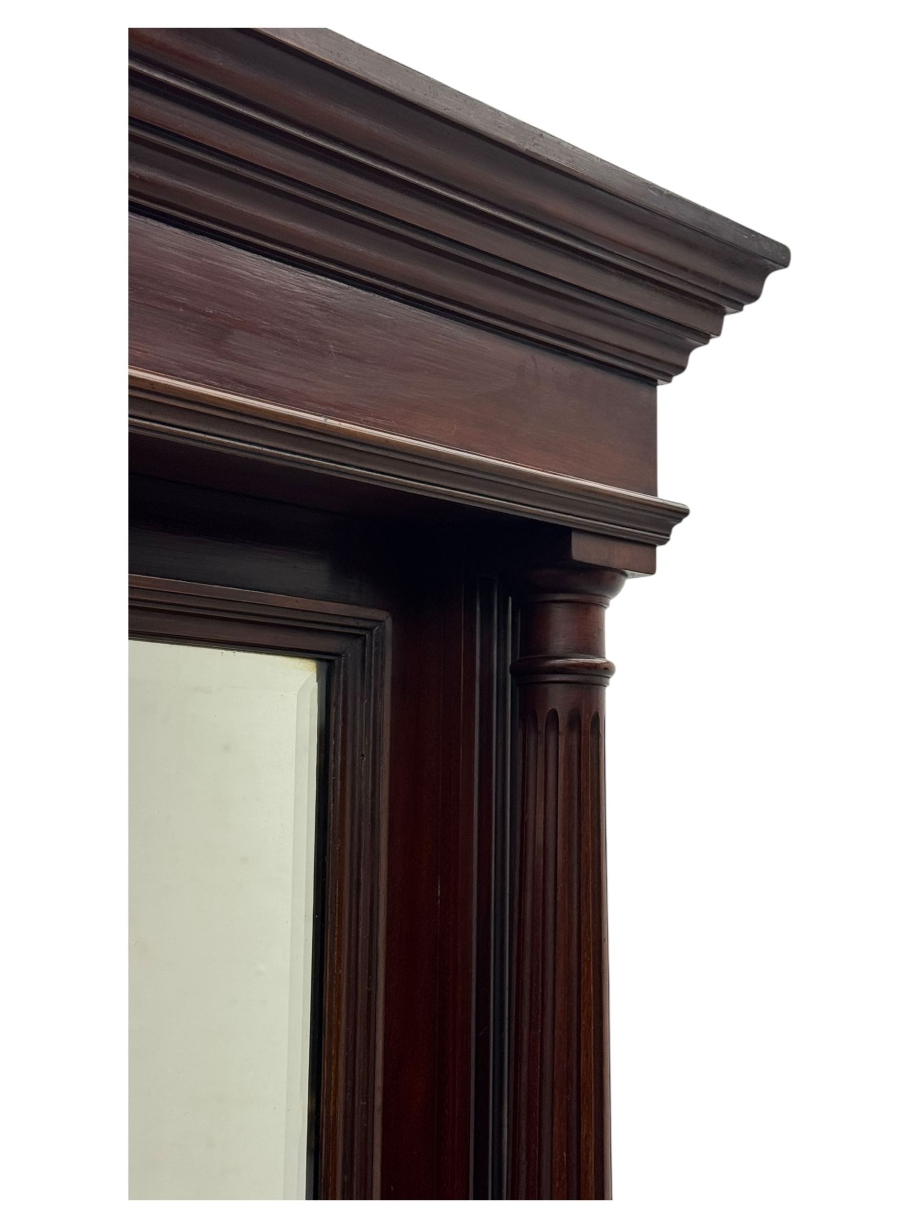 Victorian mirror back press, the arched corniced mirror back flanked by half columns, the base fitted with three drawers and four moulded panel doors with geometric detail, on a block plinth