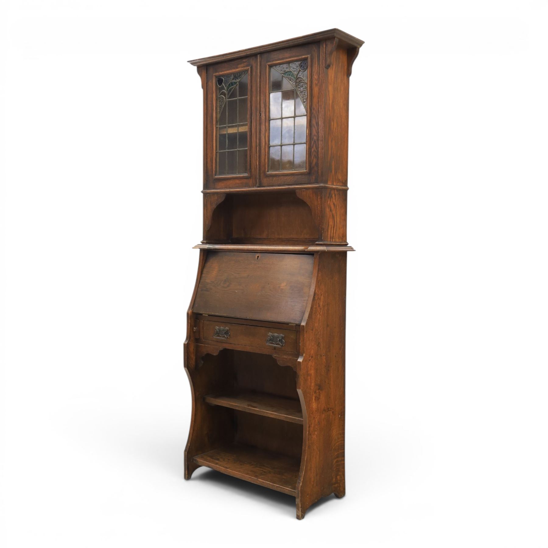 Arts & Crafts oak bureau bookcase, projecting cornice with leaded and glazed upper cabinet, the lower section with fall front section revealing a fitted interior, above shaped lower shelving 