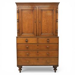 Late 19th century country oak cupboard on chest, cornice top above twin recessed panel doors with central escutcheons, flanked by turned pilasters, the lower chest with two short and three long drawers fitted with turned knob handles, on turned feet
