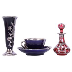 Cranberry glass scent bottle with silver overlay, together with German fluted vase with silver overlay upon a blue ground and similar teacup