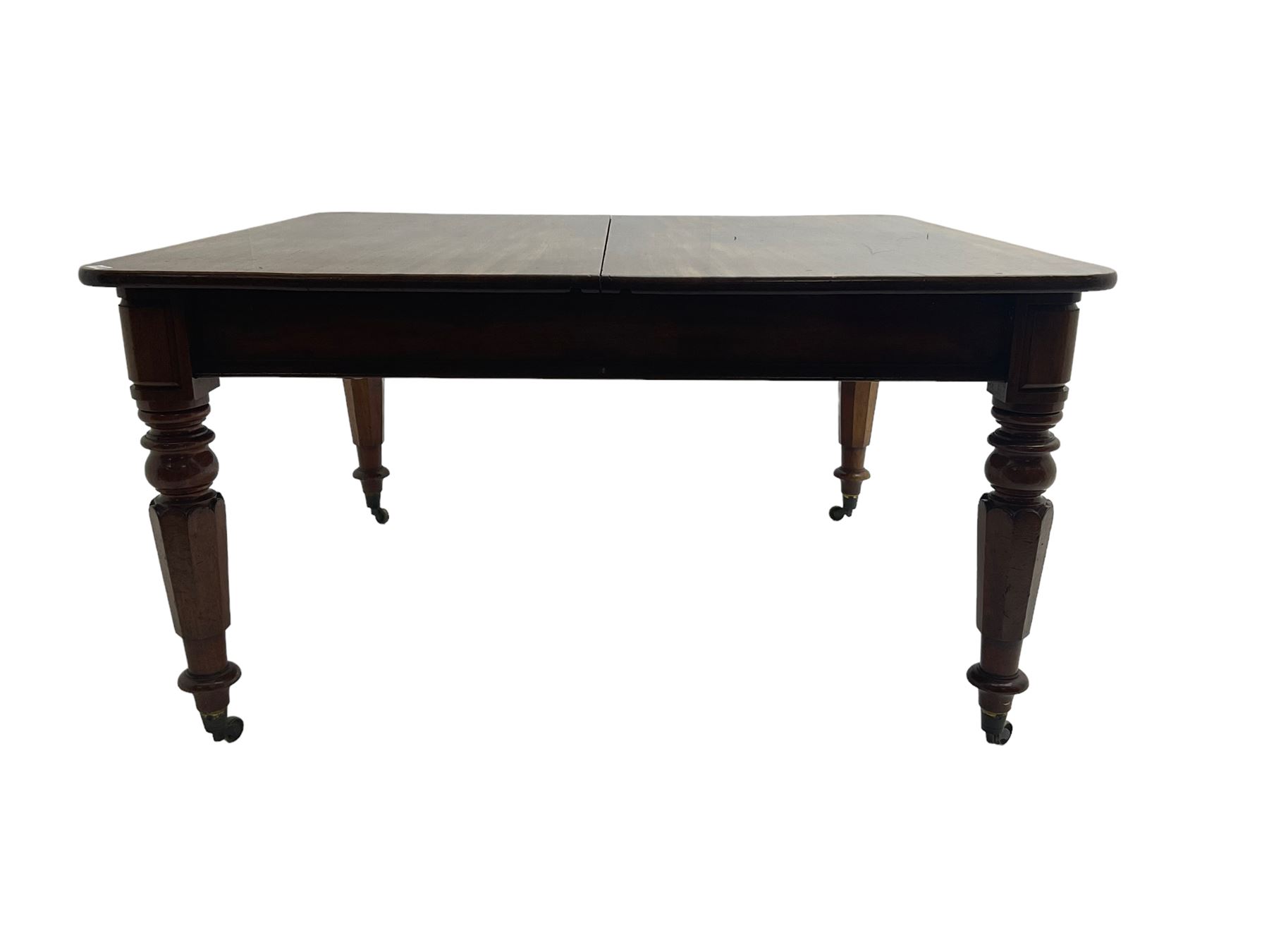 Late 19th century extending mahogany dining table, square top with banded frieze rail, raised on turned octagonal supports with  brass cups and castors, with two additional leaves