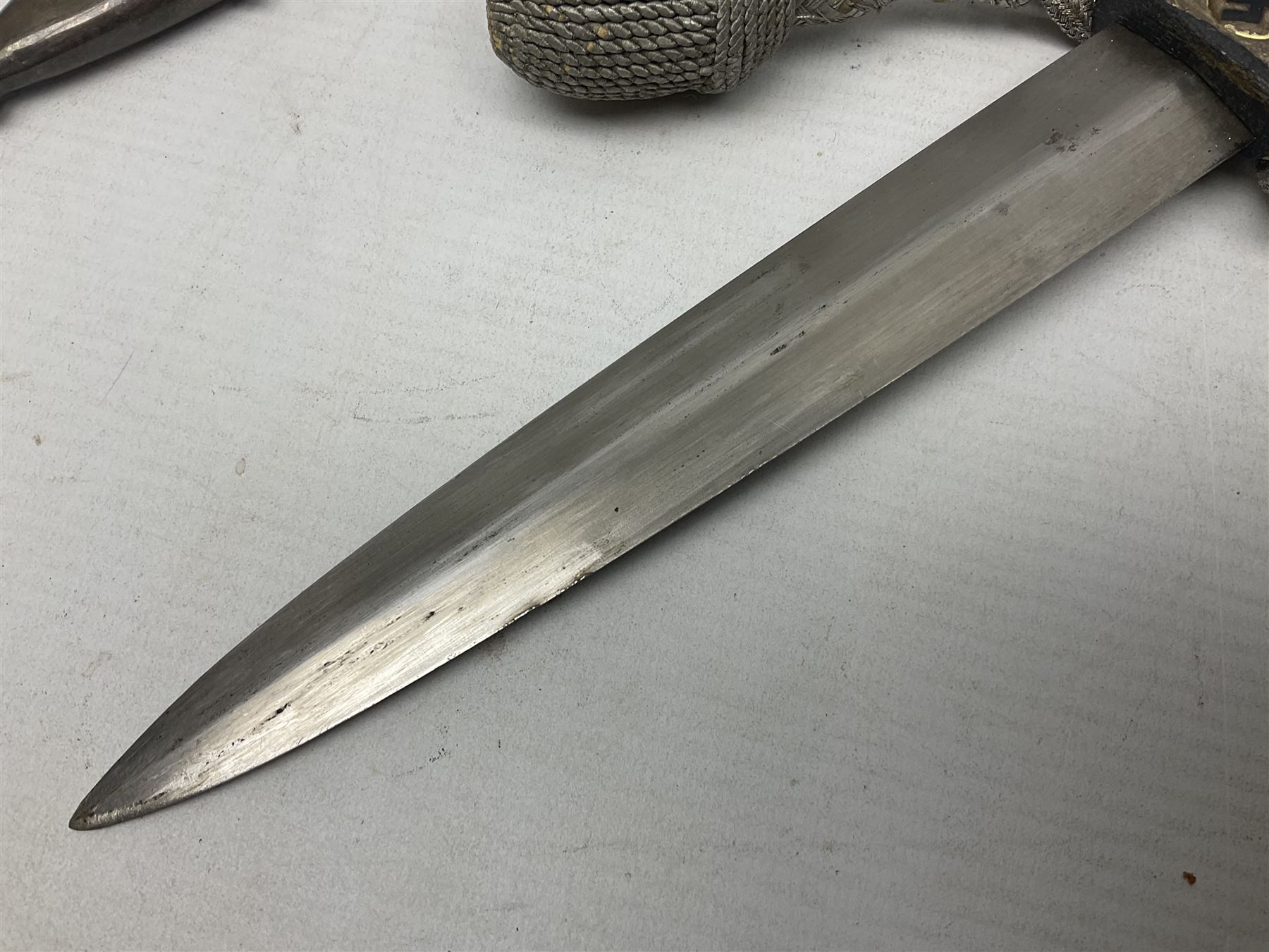 German Paul Weyersberg & Co Solingen DLV flyers dagger with 18cm steel blade, plated brass/tombac downswept cross-piece and pommel and leather covered grip, in leather and plated brass/tombac scabbard with leather hanger strap and silvered knot L35cm overall. Auctioneer's Note: After WWI Germany was forbidden an air force by the Treaty of Versailles however the Deutscher Luftsport-Verband (German Air-sport Association) was formed in March 1933 from various sports flying clubs and had branches for aeroplane, gliding and balloon flying. Under cover of the sporting DLV, many future Luftwaffe pilots trained to fly. DLV was embodied with the NSKK in March 1935 and on 1st March 1937 Luftwaffe was formed.