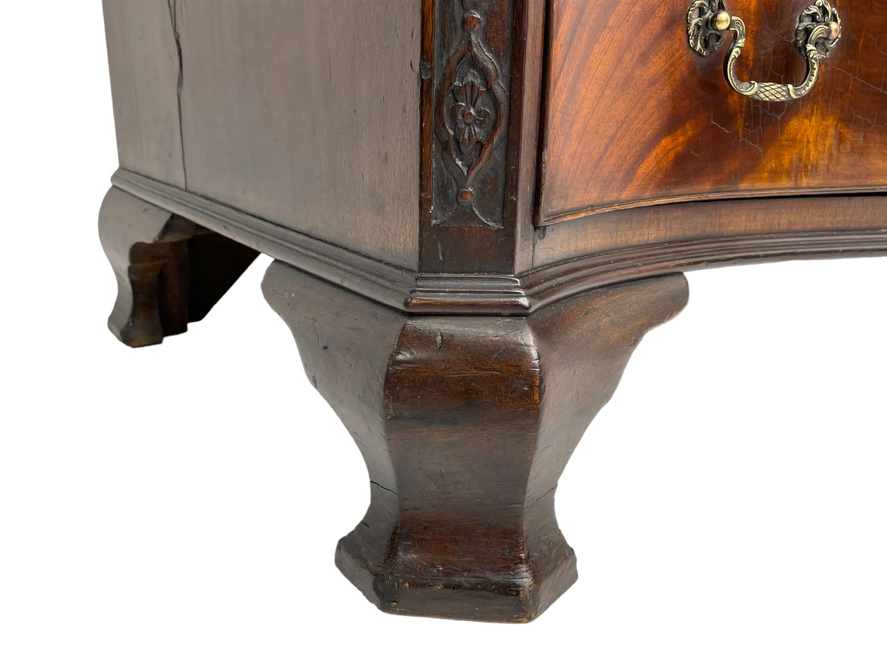 Chippendale design serpentine chest, shaped moulded top carved with repeating flower head motifs, fitted with brushing slide over four graduating drawers, pierced and foliate moulded handle plates with scrolled swan neck handles, canted upright corners carved with flower heads and strapwork, on canted ogee bracket feet