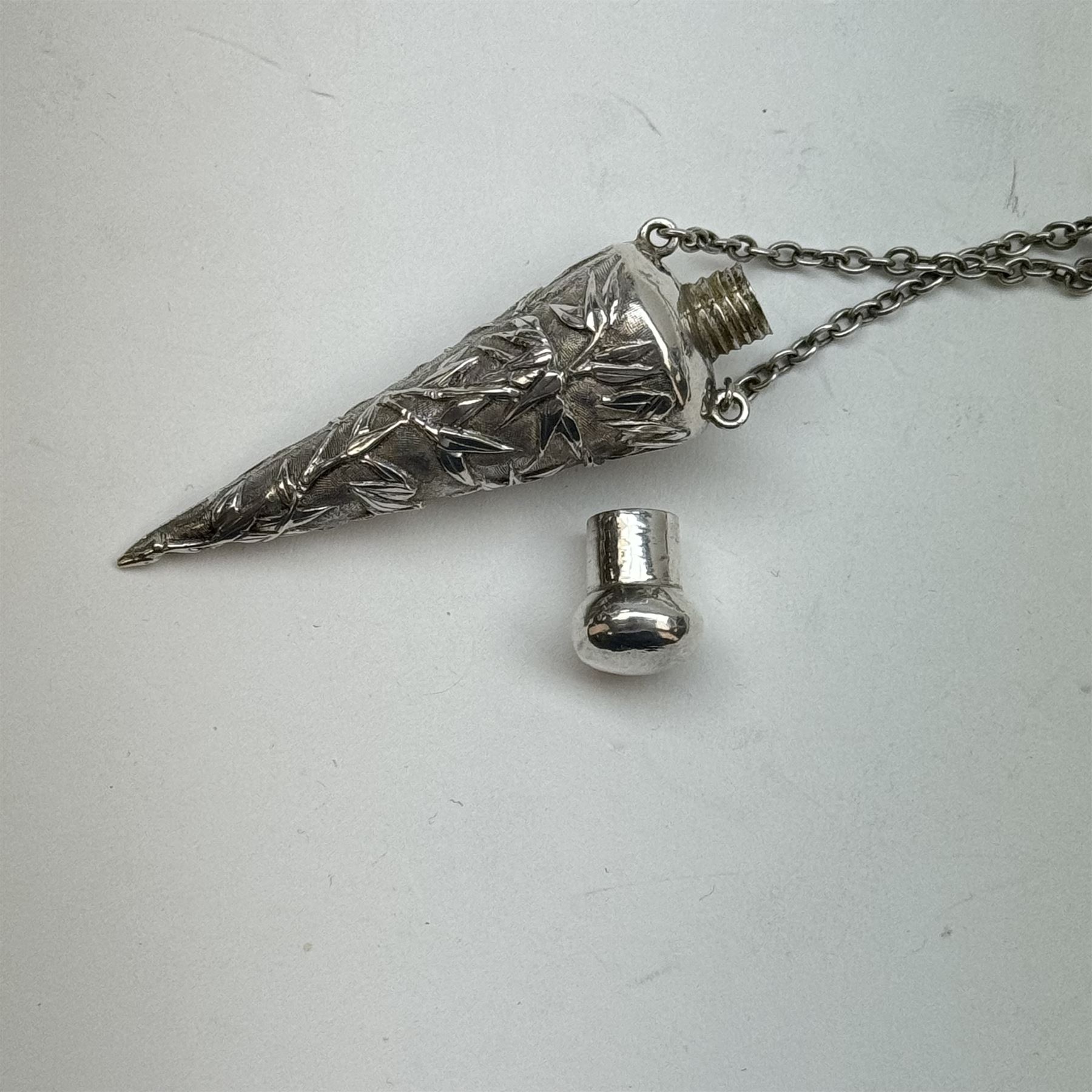 Victorian and later silver chatelaine, the shaped and foliate pierced clasp with embossed oval panel of a courting couple, hallmarked Levi & Salaman, Birmingham 1899, supporting six accessories on five chains: a circular mirror embossed with putti, hallmarked Henry Matthews, Birmingham 1911, pencil holder engraved with foliate scrolls, hallmarked Francis Webb, Birmingham 1914, conical scent bottle decorated with bamboo, (unmarked but testing as silver), aide memoire embossed with putti, hallmarked Samuel M Levi, Birmingham 1911, tape measure of compressed spherical form, hallmarked Henry Matthews, Birmingham 1899, and a purse with embossed putti, hallmarked Birmingham 1909, makers mark worn and indistinct, at longest point L31cm

