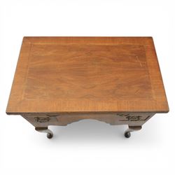 Early 20th century walnut lowboy in Queen Anne style, rectangular crossbanded top over single long drawer and two short drawers with shaped apron, fitted with brass drop handles and backplates, raised on cabriole supports terminating in pad feet
