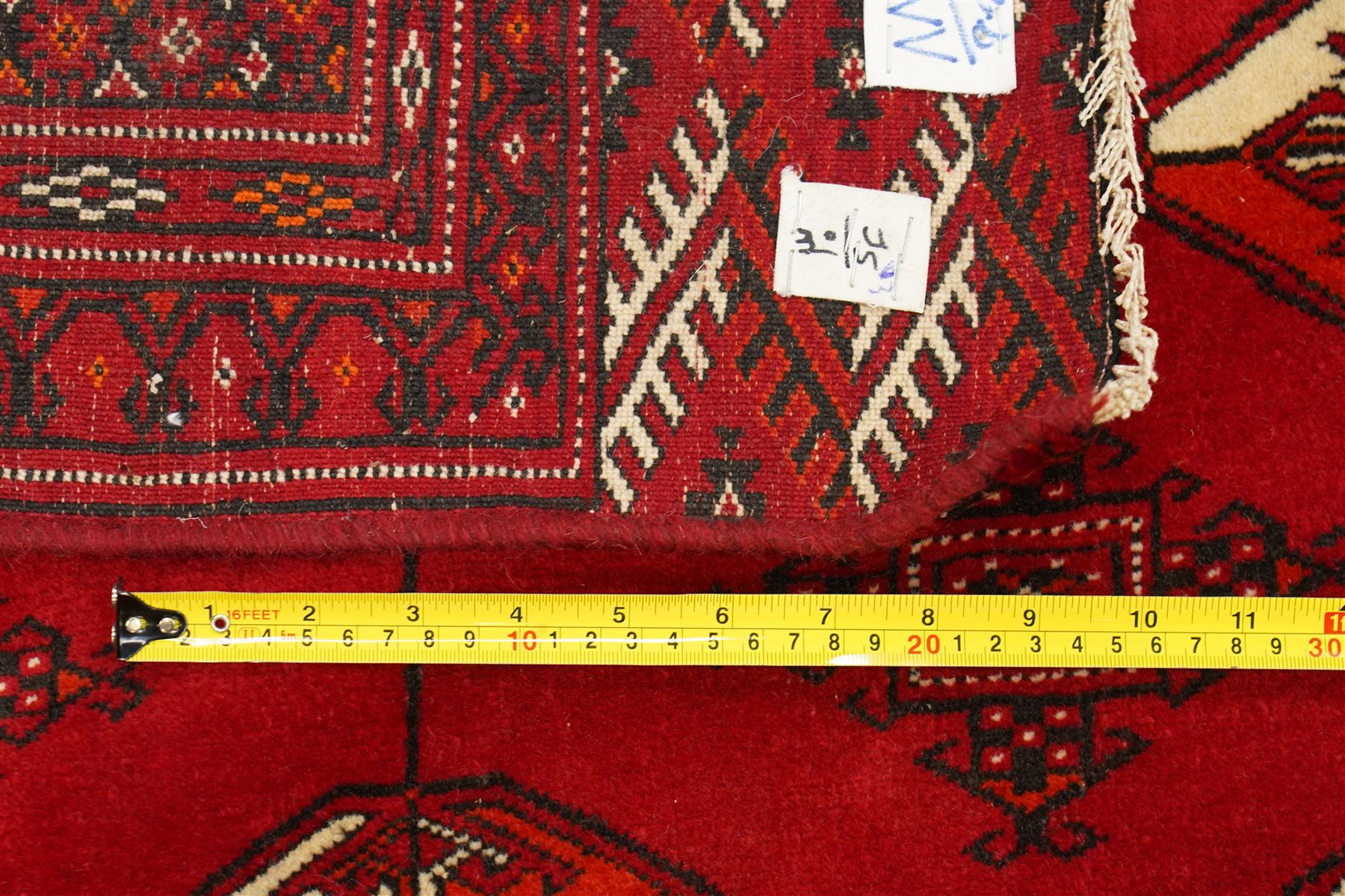 Turkmen hand-knotted carpet, deep crimson ground field, with an all-over lattice of repeating diamond guls, each enclosing angular cruiform motifs, and stylized tribal devices, interspersed with smaller geometric ornaments, main border decorated with repeating geometric motifs and stylized tribal elements, flanked by narrow guard stripes, with cotton fringe ends 