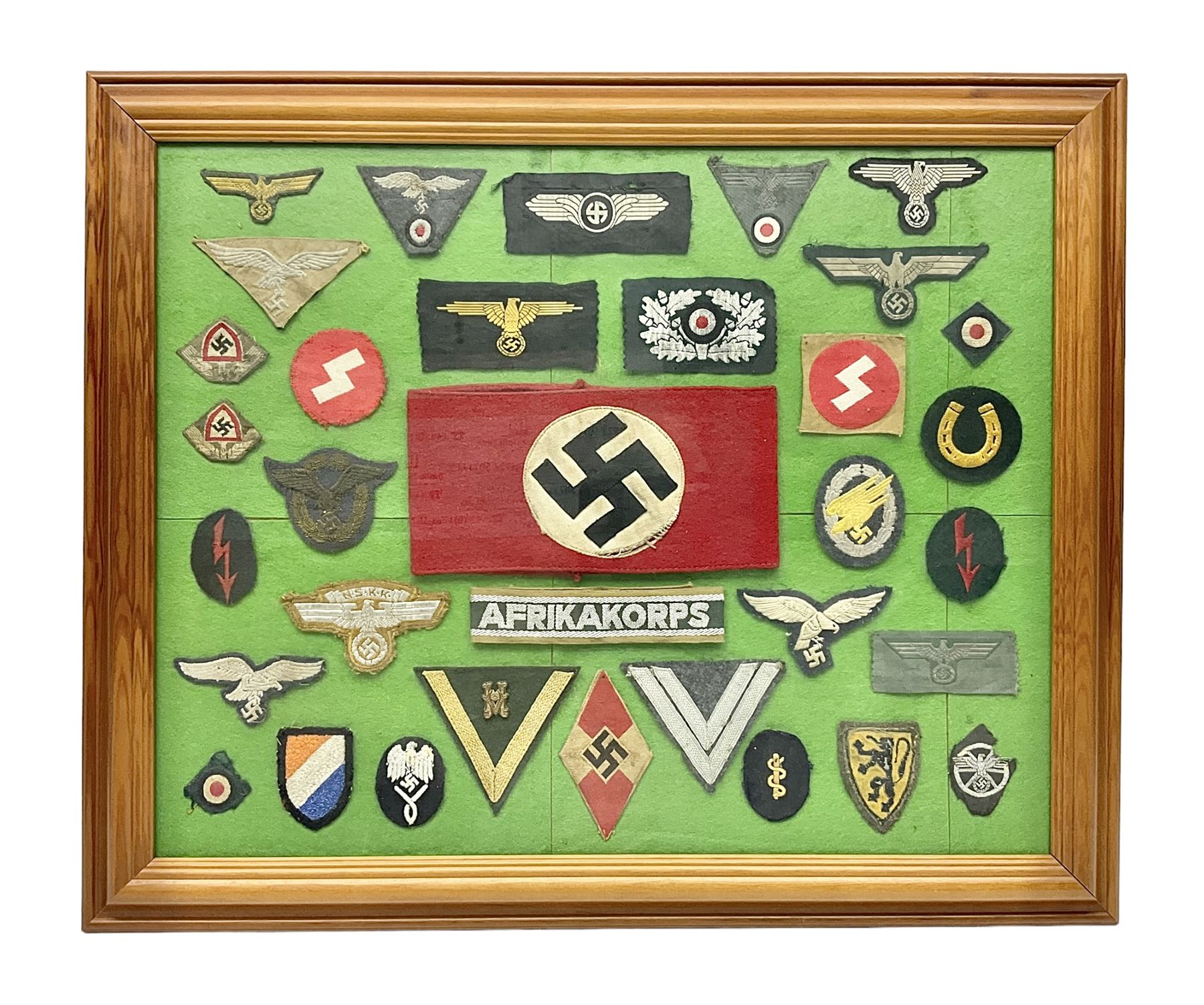 Framed display of thirty-four WWII German cloth badges including Luftwaffe pilot, Paratrooper, Afrikakorps cuff title, sleeve insignia for 'SS' Foreign Volunteers, various breast eagles including Luftwaffe, Army etc, RAD badges, Party Armband, rank and trade insignia, cap insignia etc; 40 x 50cm in modern pine frame
