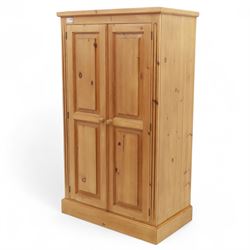 Modern stripped pine two-door wardrobe, the fielded panel doors with turned knob handles, opening to a double rail hanging interior, beneath a stepped cornice and raised on plinth base