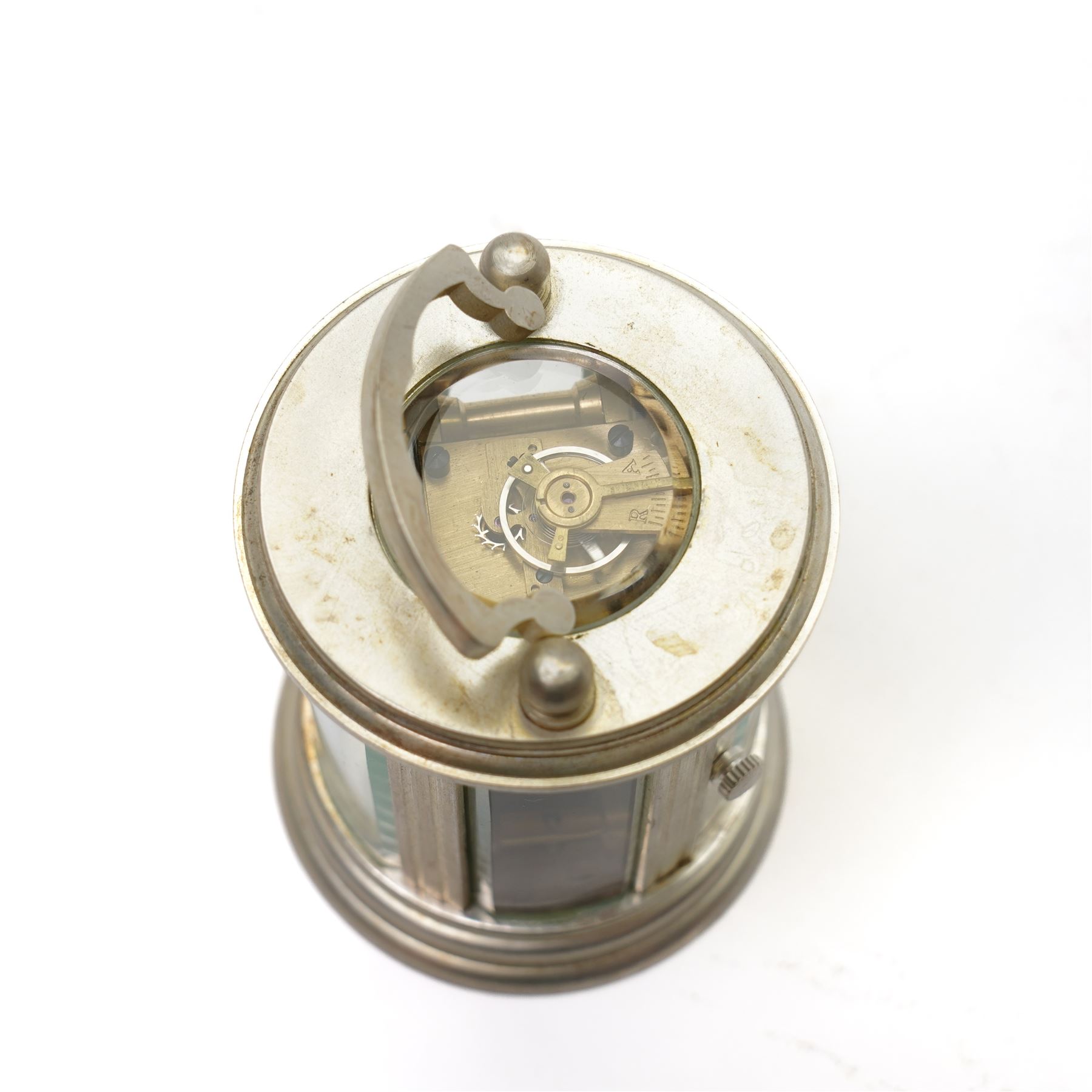 20th century-Silver plated 8-day timepiece carriage clock in an oval case, enamel dial with Roman numerals, minute track and steel moon hands, with an oval viewing class to the lever platform escapement. With key.