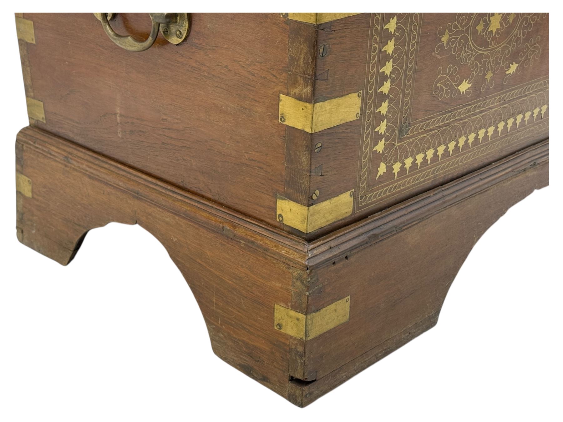 Zanzibar chest, early 20th century, of hardwood construction with brass inlaid foliate and geometric decoration to the lid, fitted interior of multiple carved compartments, with brass strapwork, side handles, and shaped bracket feet