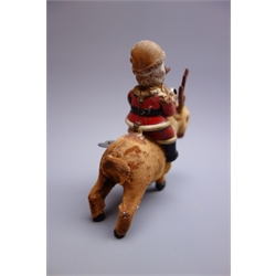  Early 20th century clockwork figure of Father Christmas with composition head and tin-plate body, riding a cloth covered reindeer with wheeled tin-plate front hoofs and integral winding key H15cm  