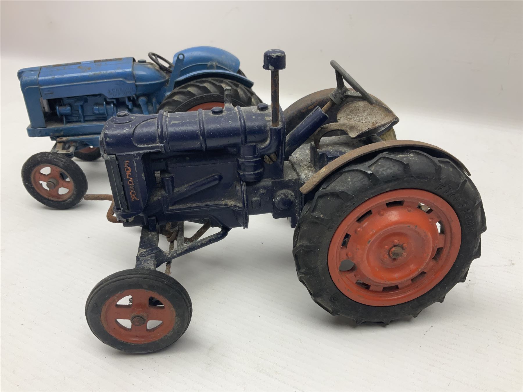 Chad Valley - two unboxed and playworn large scale Fordson tractors - No.9235 Fordson Major Tractor, dark blue diecast body, orange wheels, crank handle clockwork mechanism and 'Firestone' rubber tyres; and No.M59 New Fordson Major Tractor, blue diecast body, tinplate hinged bonnet, orange wheels and clockwork motor contained in rear wheel hub (2)