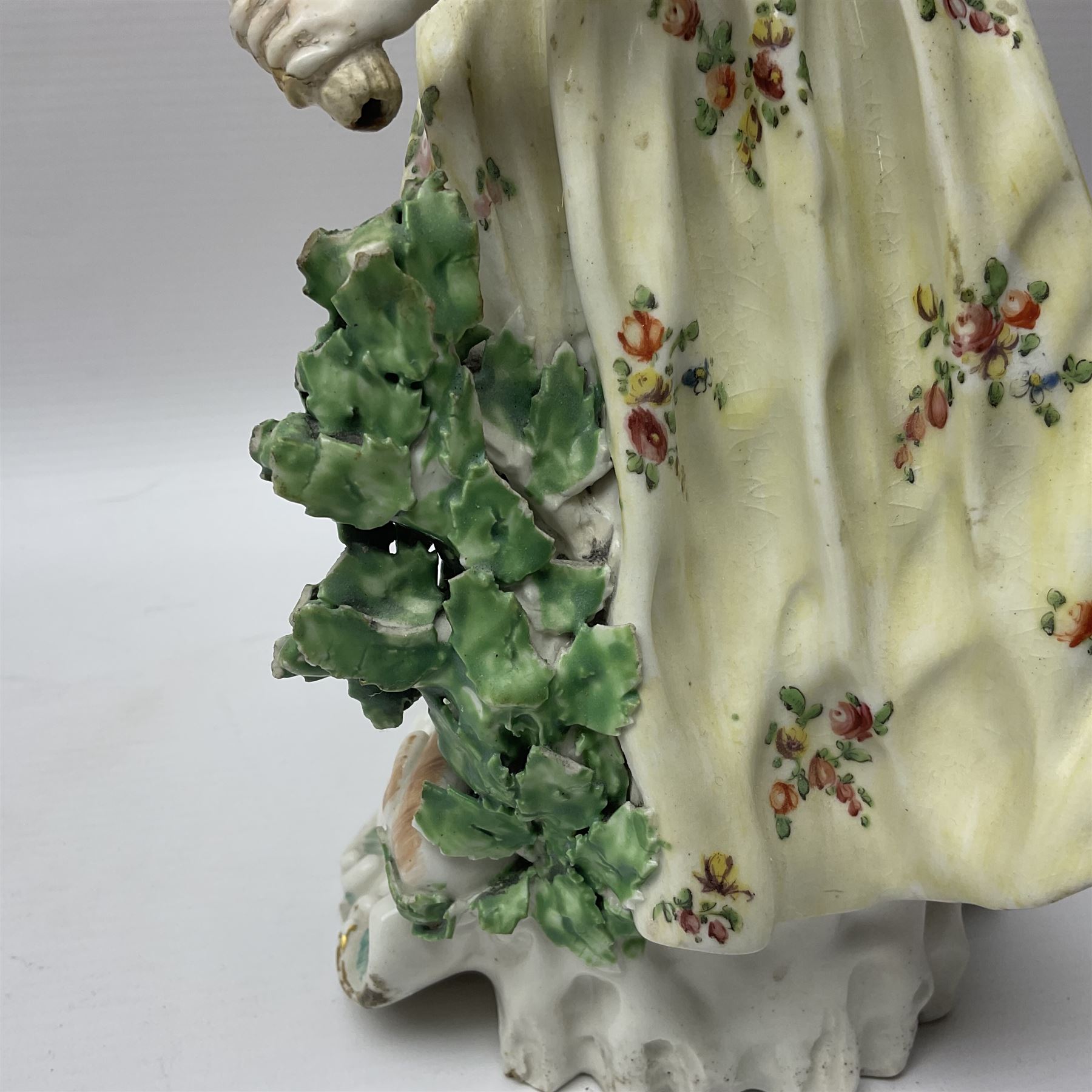 18th century Derby figure of Diana the huntress, circa 1760, modelled reaching for an arrow from quiver across her back, with recumbent hound at her feet, upon a scrolled base with bocage detail, H27.5cm