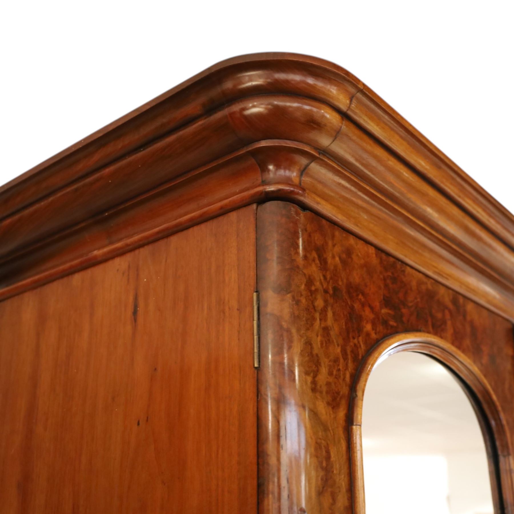 Victorian figured walnut double wardrobe, projecting moulded cornice over twin arched silvered mirrored doors, fitted with hanging rail and drawer with campaign style handle, on plinth base