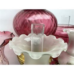 Victorian cast brass oil lamp, with fluted pink glass shade, together with two smaller brass oil lamps with pink shades and reservoirs and a pair of oil lamps, the bases modelled as putti, with pink glass reservoir  and frosted shades, tallest H70cm