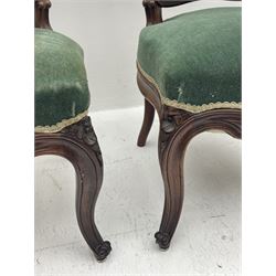 Set three Victorian rosewood drawing room side chairs, shaped and moulded frames carved with scrolls, upholstered in green velvet, serpentine sprung seats, the cabriole supports carved with flower heads