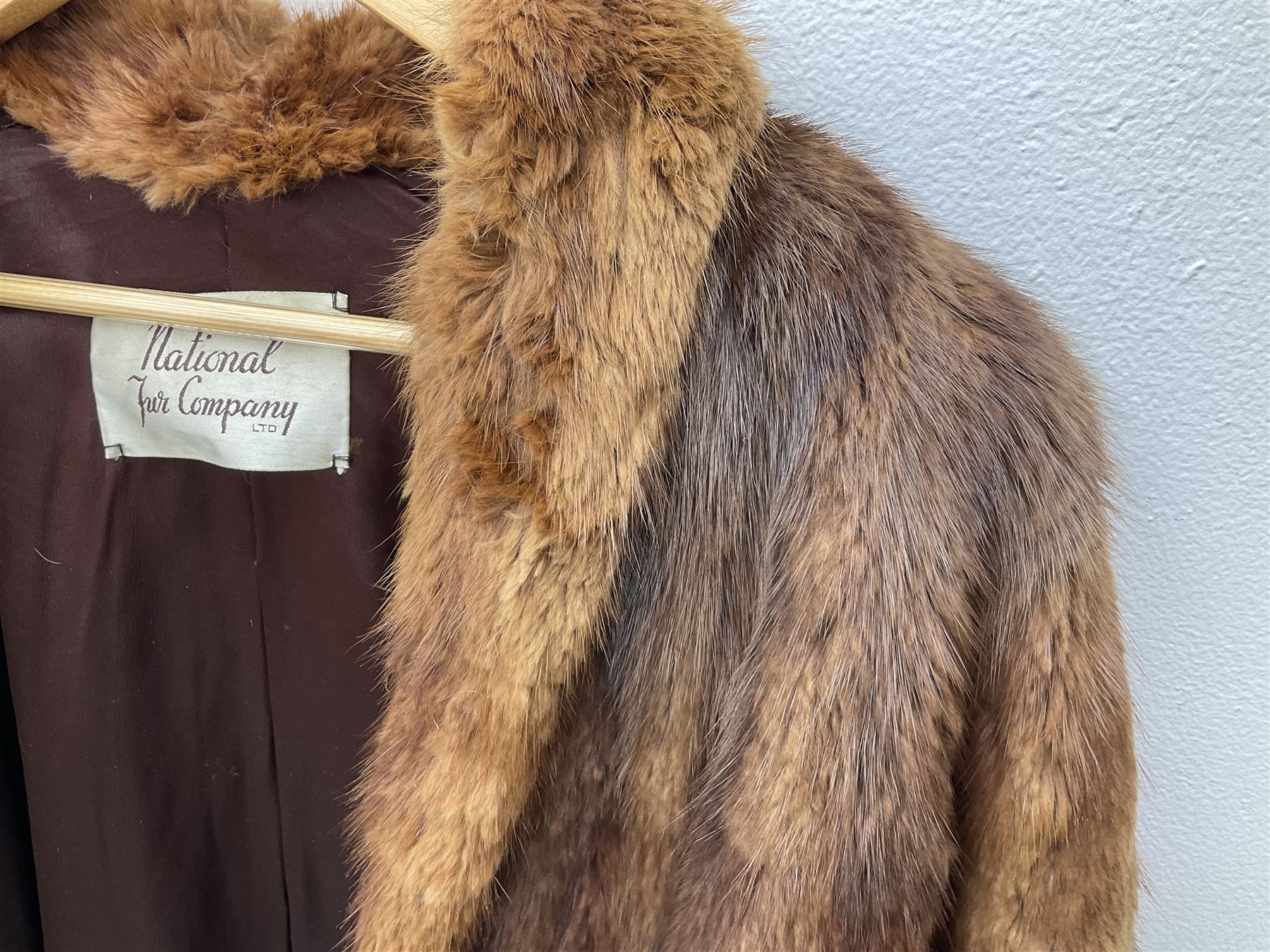 Brown mid length musquash fur coat by National Fur Company together with white rabbit cape