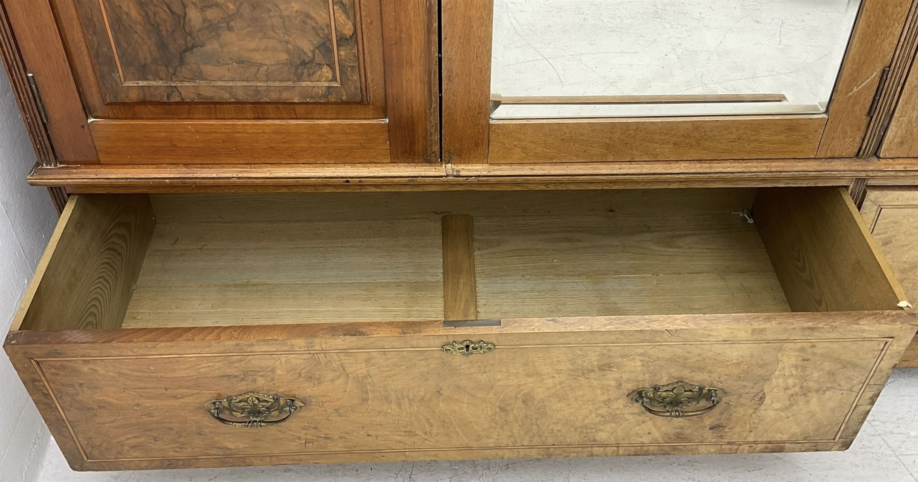 Late Victorian walnut triple combination wardrobe, projecting moulded and dentil cornice, central shaped bevelled mirror glazed door, cartouche and curled leaf carved panels over figured walnut veneered panels, fitted with drawer to base, on bracket feet
