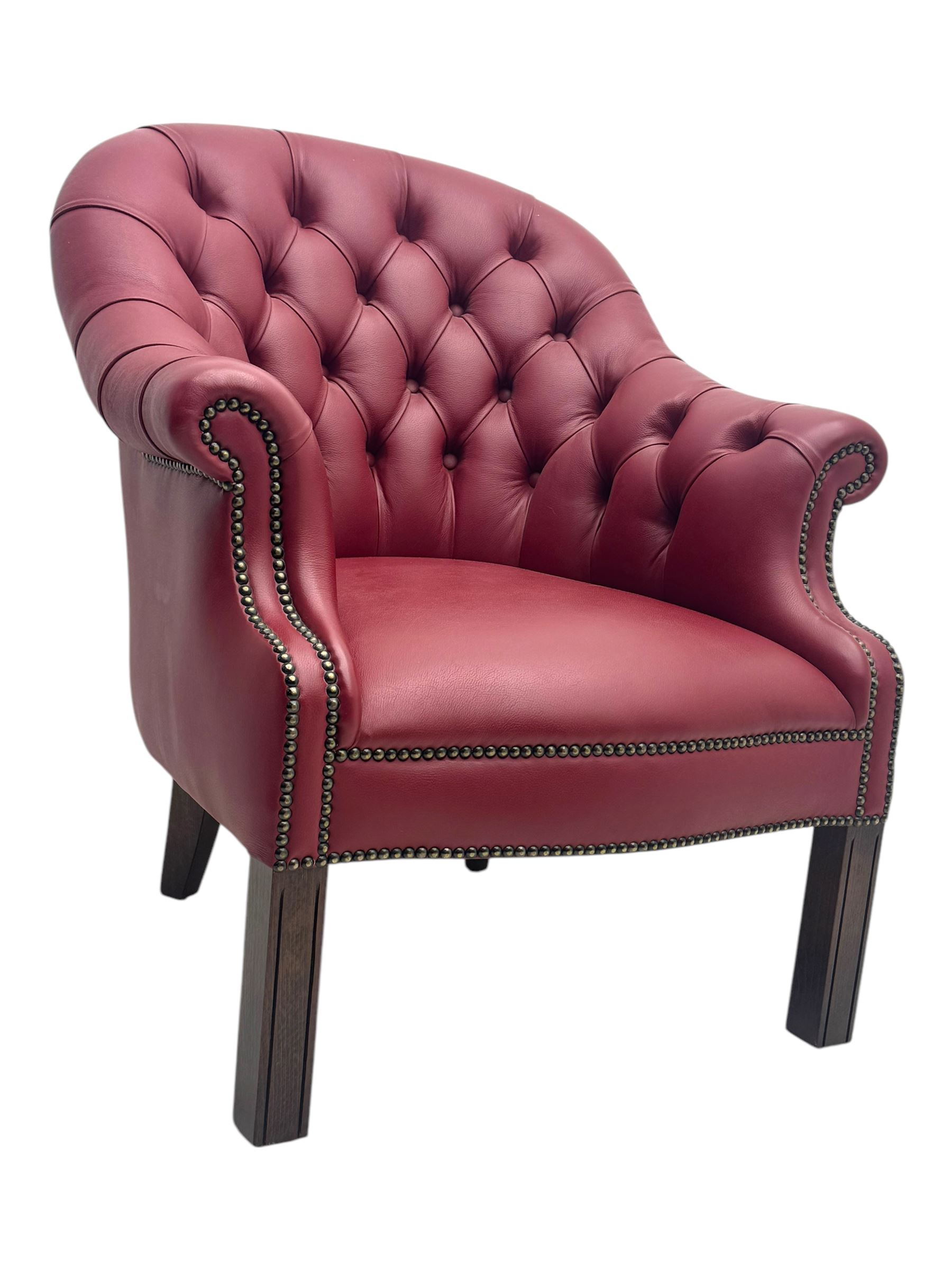 Kingsgate - contemporary 'Devon' bucket armchair, upholstered in red leather with buttoned backrest, rolled arms and brass stud detailing, raised on four dark wood supports with vertical carving