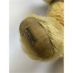 Merrythought Hygienic Toys large 'Magnet' teddy bear c1930s with plush body, swivel jointed head with glass eyes and vertically stitched nose and mouth and jointed limbs,  celluloid wishbone button to right ear and stitched label under right pad H22