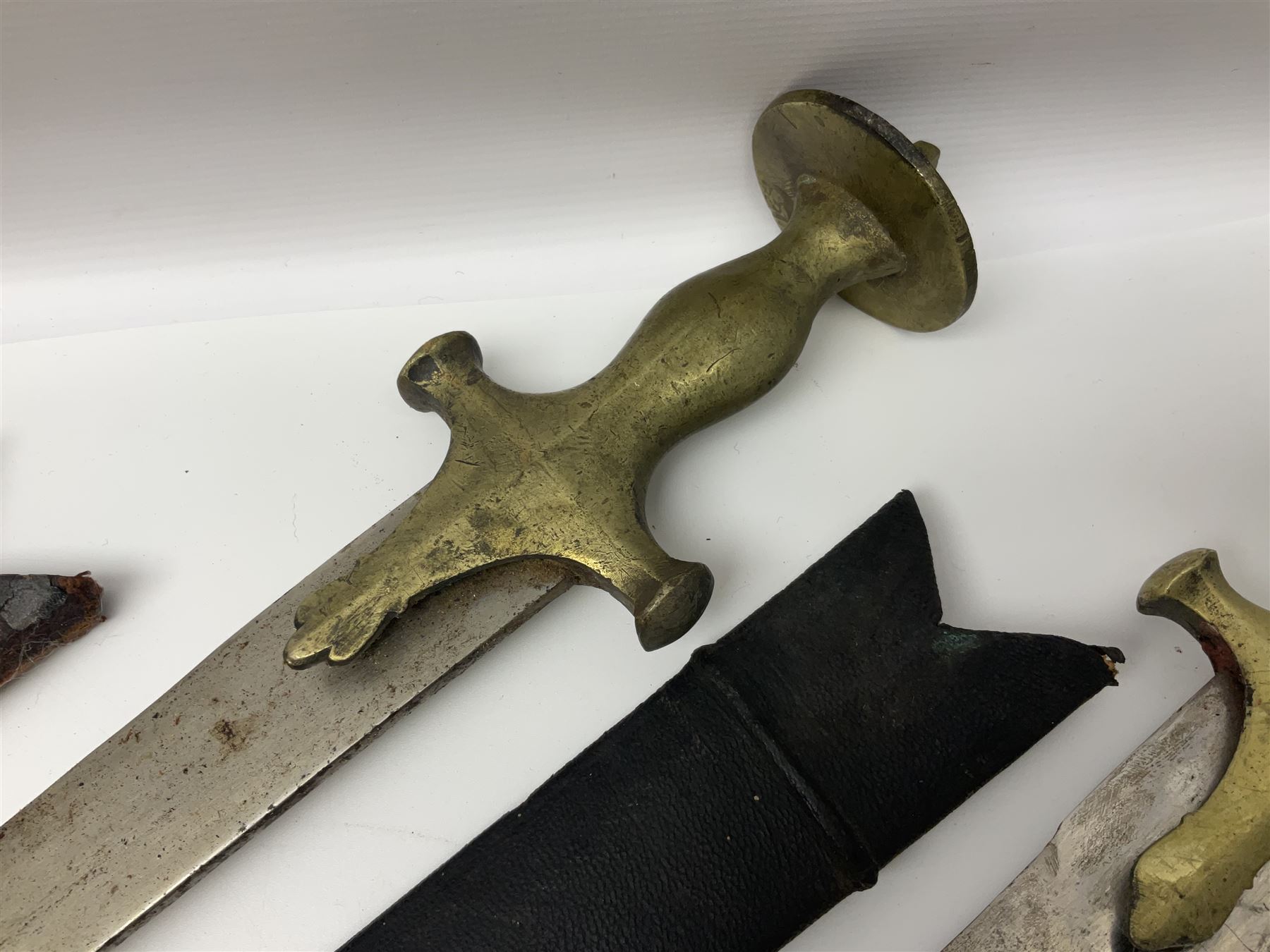 Four Indian tulwar swords; three with cast brass hilts and one with iron hilt; longest blade 81cm; all with scabbards (4)