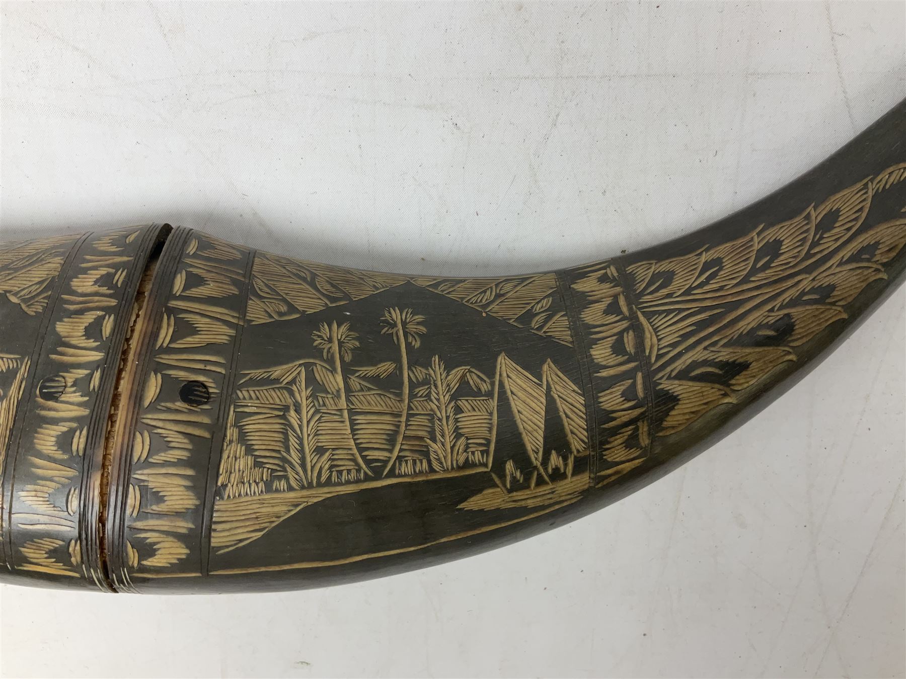 Carved water buffalo horn wall pocket, engraved with landscape scene with patterned borders with pierced foliate panel, together with a pair of horns with similar engraved decoration, L47cm