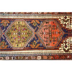Persian Iranian wool runner, with a series of stepped hexagonal medallions in rust, olive and ivory against and deep navy field, the medallions are filed with floral and latch-hook motifs, framed by and ivory guard border with geometric rosettes, flanked by a rust outer band