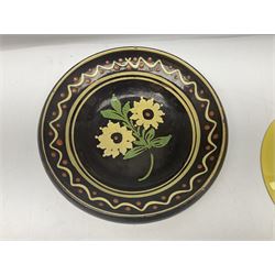 Early 20th century brown glazed bowl, decorated with slip type decoration of flowers, together with a Park Lane Ware yellow plate with applied pewter bird decoration
