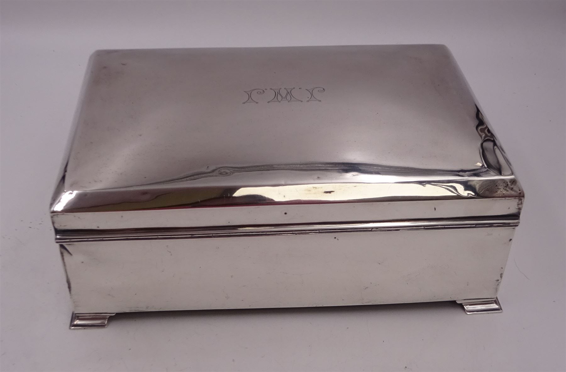1920s silver mounted presentation cigarette box, of rectangular form, with engraved initials J.W.J and dated 1902-1927 to slightly domed hinged cover, opening to reveal compartmentalised softwood interior, upon four bracket feet, hallmarked Birmingham 1920, maker's mark worn and indistinct, H9cm, W23cm, reputedly given to John William Johnson, father of Amy Johnson,  famous for being the first long distance (to Australia) solo female pilot, and first female British grounds engineer, for his silver wedding anniversary