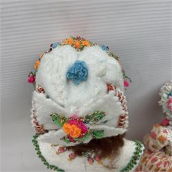 Anna Meszaros Hungary - three hand made needlewrok figurines - each wearing a lon floral dress and bonnet and holding a bouquet of flowers, tallest H32cm (3)  Auctioneer's Note: Anna Meszaros came to England from her native Hungary in 1959 to marry an English businessman she met while demonstrating her art at the 1958 Brussels Exhibition. Shortly before she left for England she was awarded the title of Folk Artist Master by the Hungarian Government. Anna was a gifted painter of mainly portraits and sculptress before starting to make her figurines which are completely hand made and unique, each with a character and expression of its own. The hands, feet and face are sculptured by layering the material and pulling the features into place with needle and thread. She died in Hull in 1998.