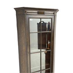 Early 20th century oak corner display cabinet, enclosed by glazed door, on spiral turned supports joined by undertier 