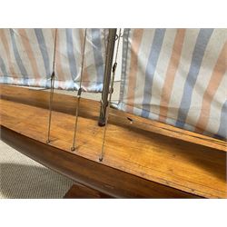 Large pond yacht with simulated planked mahogany deck, mahogany hull, wooden keel and stern fin and tubular aluminium mast with two sails; on wooden stand L131cm H on stand 177cm