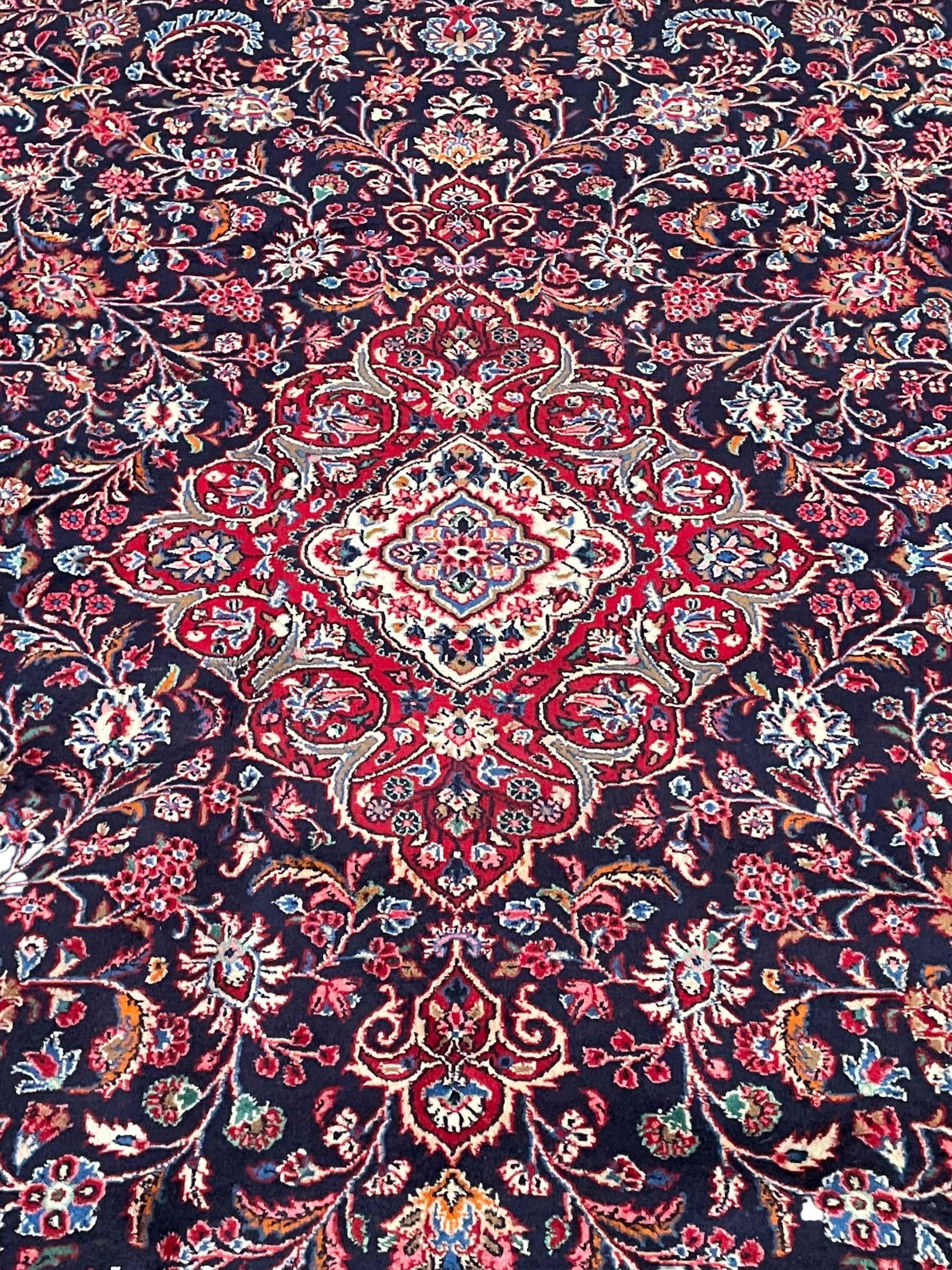 Persian Hamadan indigo ground carpet, the field decorated with central rectangle and outer band, overall floral pattern with cusped central medallion and surrounding leafy branches with palmettes, the border with scrolling branches decorated with further palmettes, within floral pattern guard stripes