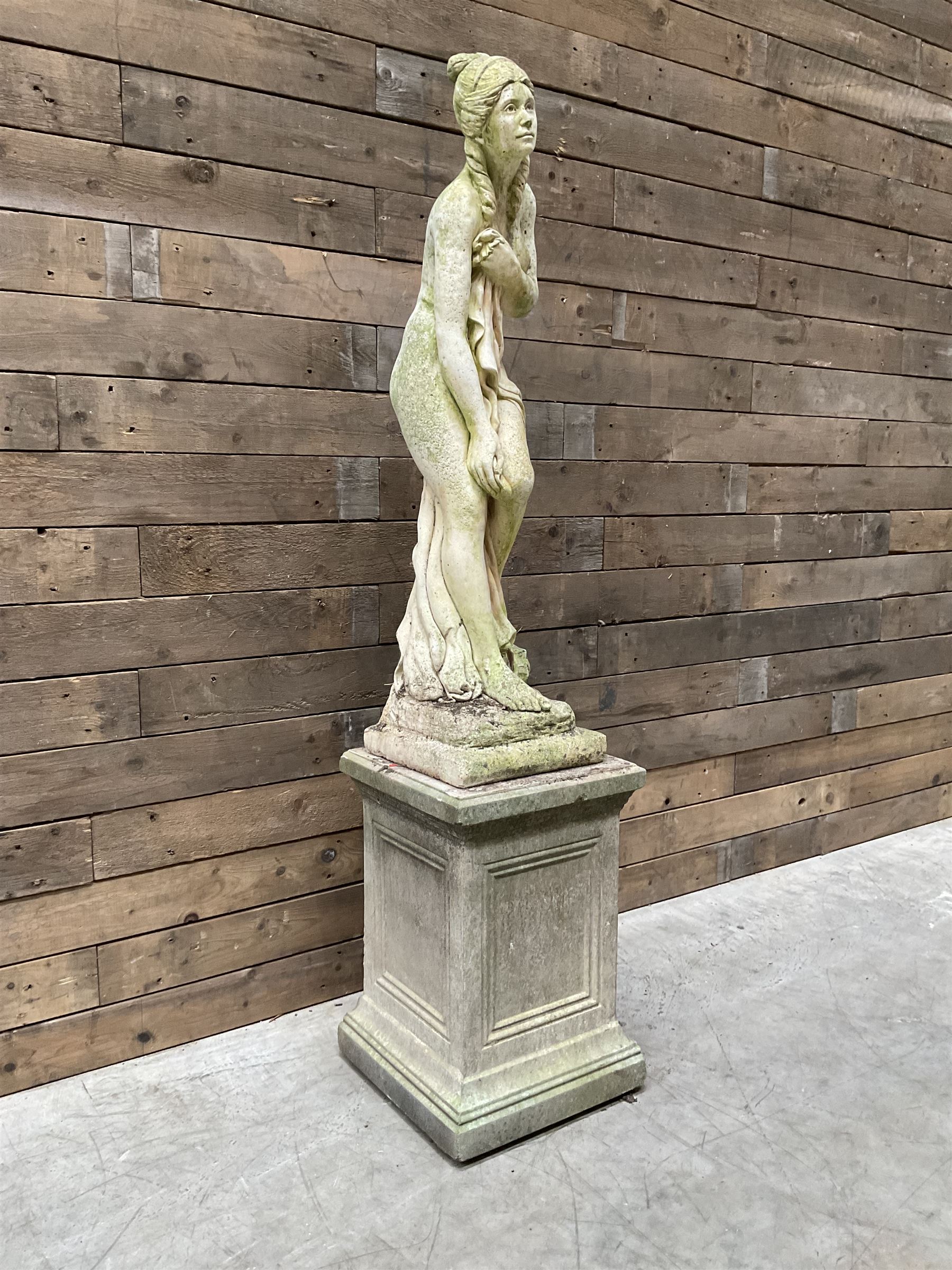 Cast stone garden figure of a bathing lady, raised on square plinth