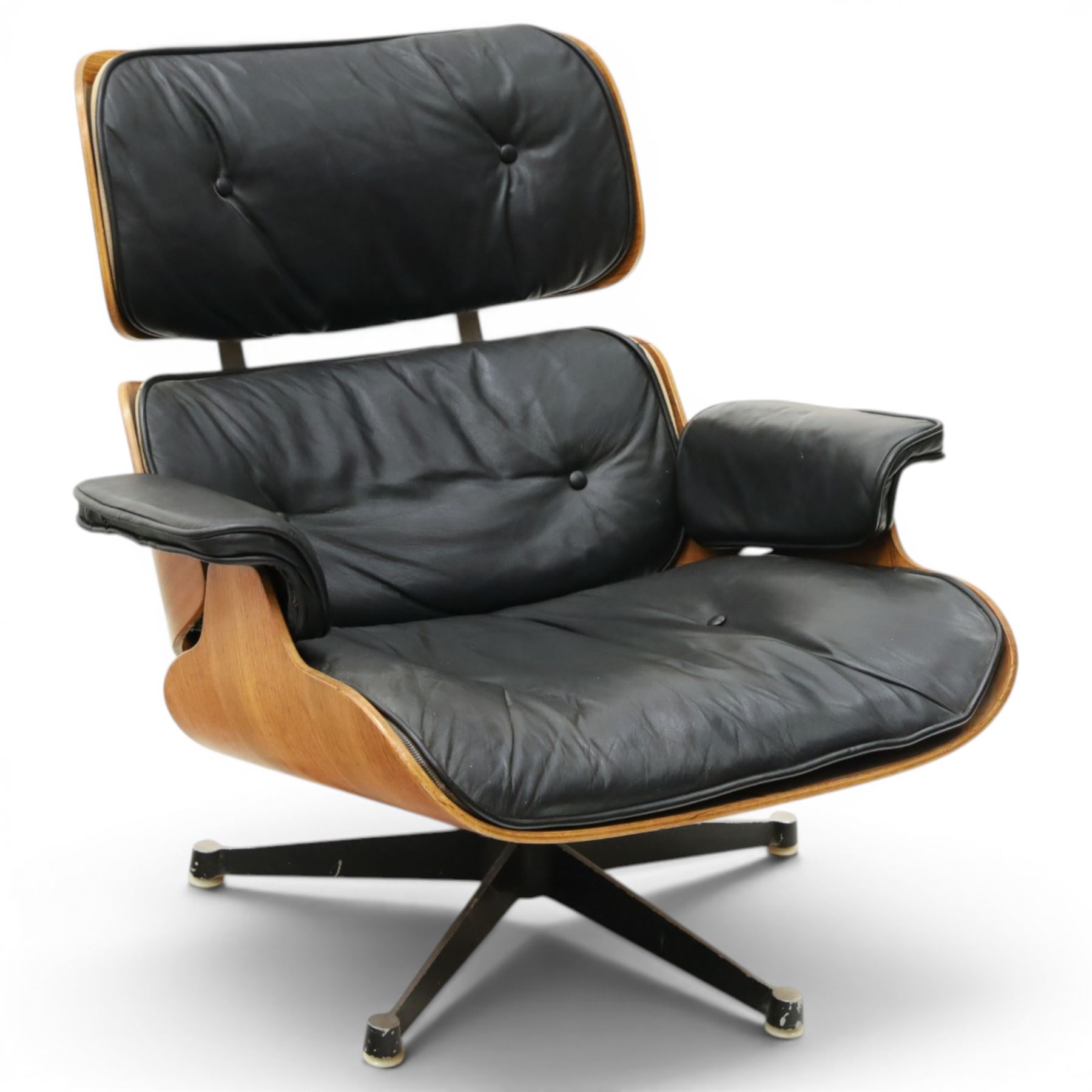 Charles and Ray Eames for Herman Miller - lounge chair, moulded veneered plywood shell with buttoned black leather upholstery, separate headrest and back cushions, padded armrests, on black cast aluminium five-star swivel base, manufactured under licence by Hille of London