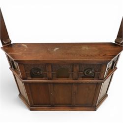 Old Charm - carved oak bar with three bar stools and associated Old Charm drinks cabinet, carved top with channels for glassware beneath, bar surface above glazed panels, shelves for glassware to the back, associated Old Charm drinks cabinet with fall front linenfold carving, above twin doors with shelved interior