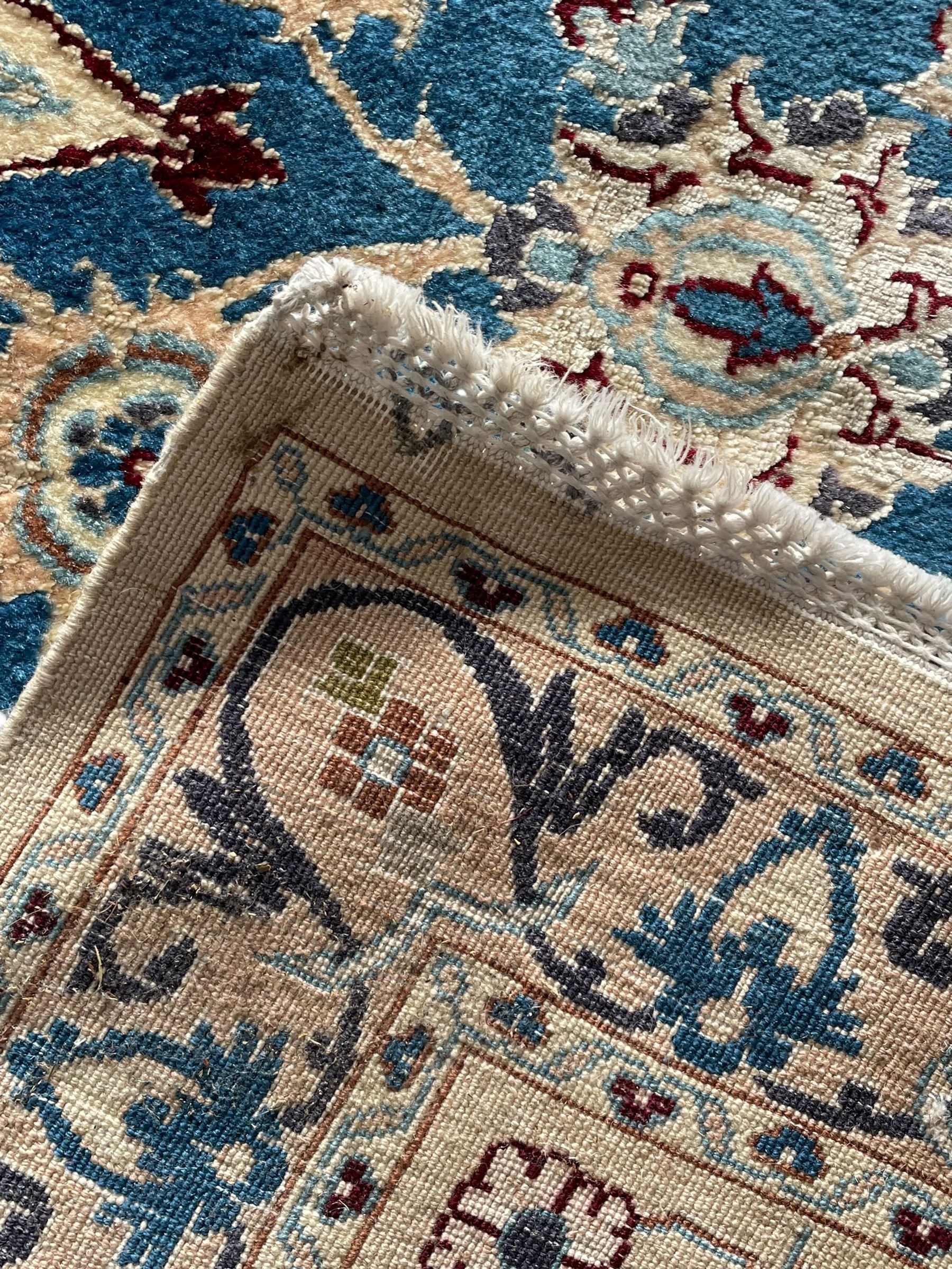 Persian Nain blue and ivory ground rug, wool with silk inlay, overall arabesque design, central medallion surrounded by interlacing and scrolled leafy branches and palmettes, the scrolling border decorated with stylised plant motifs, within guard stripes