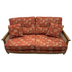 Ercol medium elm framed three seat bergere sofa, and pair of matching armchairs upholstered in red fabric