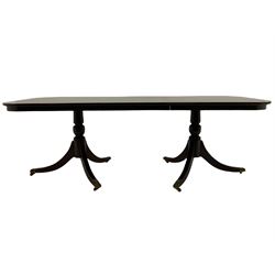Regency style mahogany twin pedestal dining table, two D-ends and central additional leaf, on turned pedestals with splayed supports terminating at brass paw cups and castors