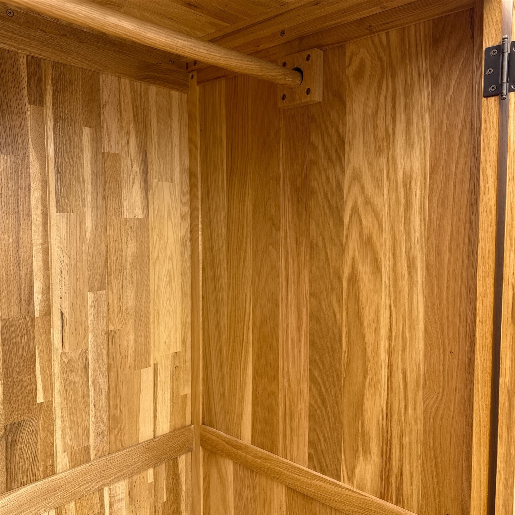 Modern light oak double wardrobe, with twin panelled doors enclosing hanging rail and full-height interior, above a deep lower drawer with recessed handle, shaped stiles
