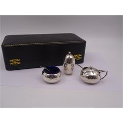 1950s silver three piece cruet set, comprising pepper shaker, open salt, mustard pot and cover, engraved with ribbon swags, hallmarked Joseph Gloster Ltd, Birmingham 1956, salt and mustard pots with blue glass liners, together with two condiment spoons, hallmarked, all within a fitted silk and velvet lined case 