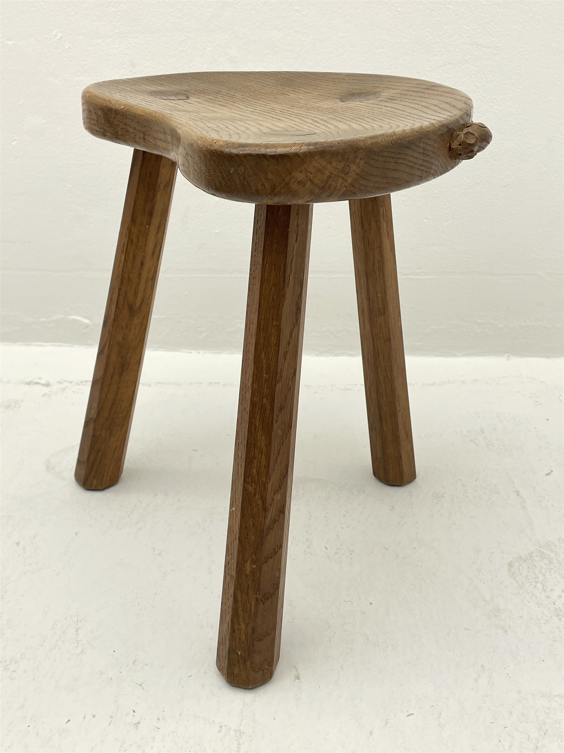 'Mouseman' oak three legged stool with dished kidney shaped seat, tapered octagonal supports, with carved mouse signature, by Robert Thompson of Kilburn 