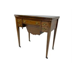 Edwardian inlaid mahogany games or work table, rectangular fold-over top inlaid with stylised dragon ivorine decoration and stringing, fitted with one long flanked by four small drawers over sewing compartment drawer, raised on square tapering supports with castors