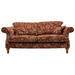Traditional shape three seat sofa, upholstered in red fabric with trailing floral pattern, on turned front feet