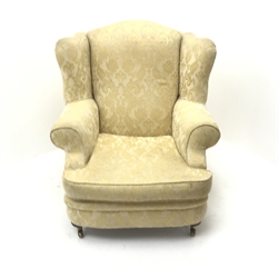 Licoln House wing back armchair, upholstered in a pale gold chenille fabric with floral pattern, shaped back, scrolled arms on turned supports, W91cm