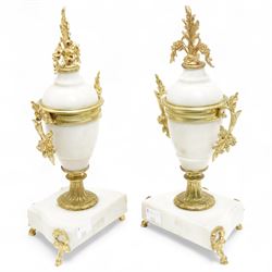 French-Early 20th century 8-day white marble and gilt metal striking portico mantle clock and garniture, Parisian drum movement with a white enamel dial, Arabic numerals and garland swags, two train countwheel striking movement sounding the hours and half hours on a bell. With a matching pair of conforming urns with gilt mounts. 