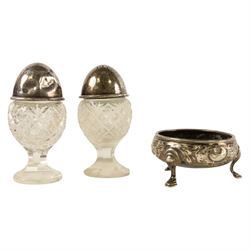 George III silver open salt with embossed floral decoration and a pair of cut glass cruets...