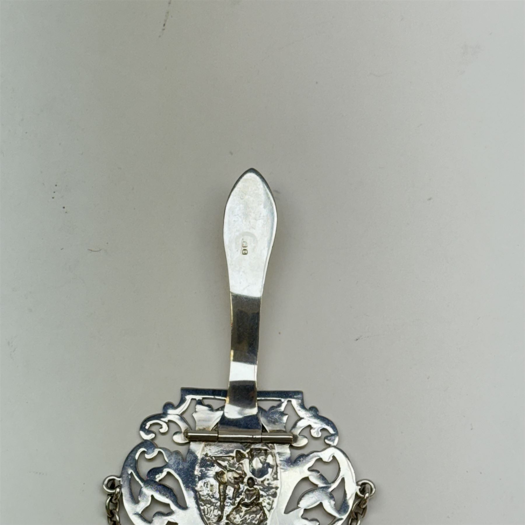 Victorian and later silver chatelaine, the shaped and foliate pierced clasp with embossed oval panel of a courting couple, hallmarked Levi & Salaman, Birmingham 1899, supporting six accessories on five chains: a circular mirror embossed with putti, hallmarked Henry Matthews, Birmingham 1911, pencil holder engraved with foliate scrolls, hallmarked Francis Webb, Birmingham 1914, conical scent bottle decorated with bamboo, (unmarked but testing as silver), aide memoire embossed with putti, hallmarked Samuel M Levi, Birmingham 1911, tape measure of compressed spherical form, hallmarked Henry Matthews, Birmingham 1899, and a purse with embossed putti, hallmarked Birmingham 1909, makers mark worn and indistinct, at longest point L31cm

