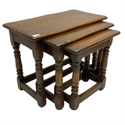 Solid oak nest of three tables, turned supports joined by stretchers