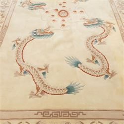 Late 20th century Chinese wool carpet, cream field with five stylized dragons arranged in a circular formation around a central flaming pearl motif, dragons depicted with elongated bodies and clawed feet amongst stylized cloud forms, enclosed within a narrow inner border and a wider outer border decorated with traditional Chinese motifs and symbols